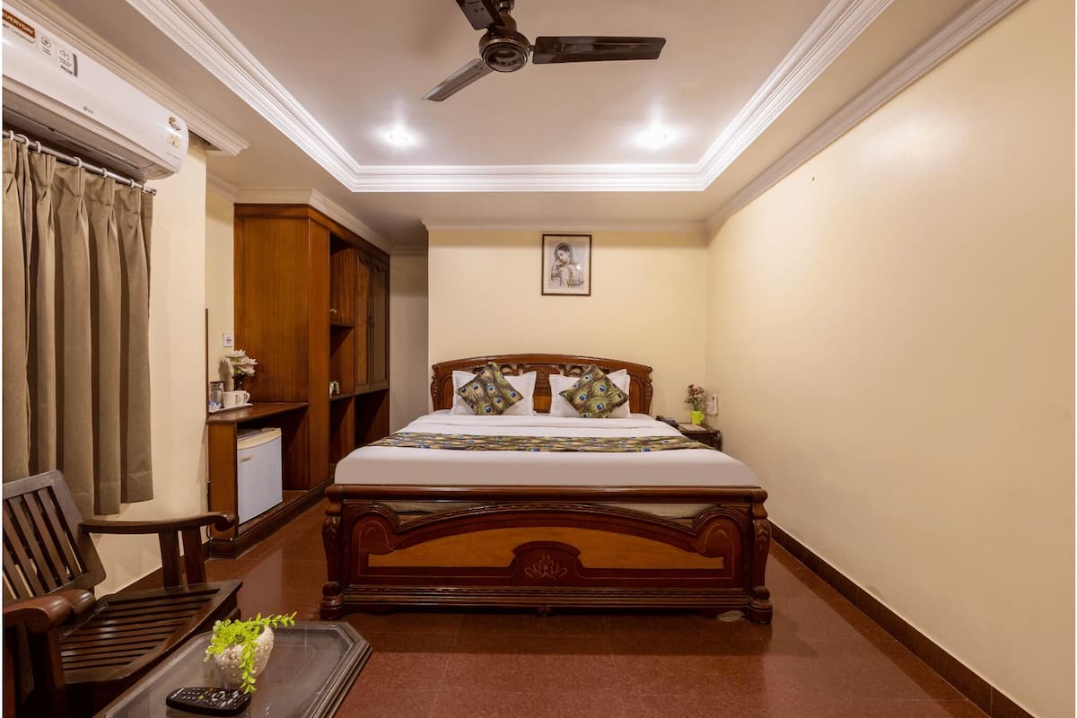 A neatly arranged bedroom with a wooden bed, a ceiling fan, a small desk, and a chair.