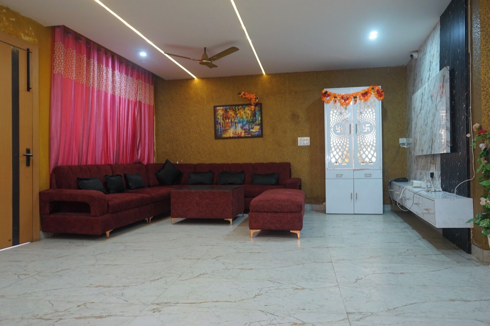 A living room with a sectional sofa, a ceiling fan, and a decorative door.
