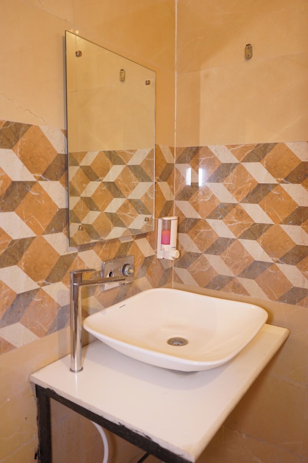 A bathroom with a white sink, a mirror, and a geometric patterned wall.