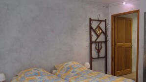 Ein Schlafzimmer mit Bett, Nachttischen, einer Holztür und einem Wandspiegel.