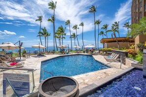 A swimming pool with lounge chairs and umbrellas, surrounded by palm trees and a clear sky. - Mana Kai 811 - Oceanfront, Top Floor, Stunning Renovation, 2BR, Kings, Split AC (Kihei)