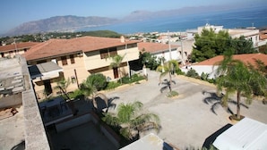 A residential area with buildings, a paved courtyard, and palm trees. - Residence Marino (Balestrate)