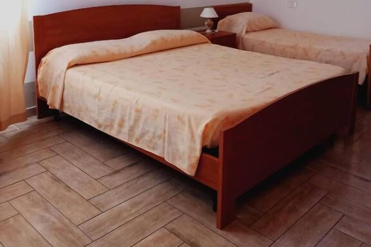 A bedroom with two beds, wooden flooring, and a striped wall design.