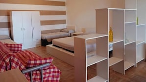A modern bedroom with a bed, a sofa, a wardrobe, and built-in shelving. - Residence Marino (Balestrate)