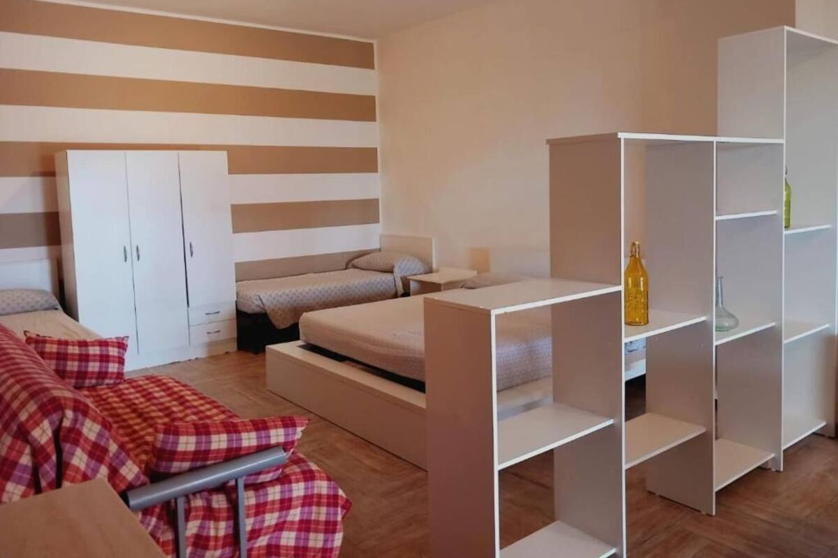 A modern bedroom with a bed, a sofa, a wardrobe, and built-in shelving.