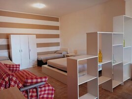 Un dormitorio moderno con cama, sofá, armario y estanterías empotradas.