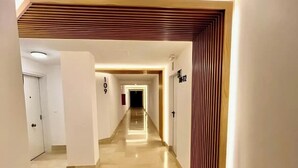 Een moderne hotelgang met een gepolijste vloer, een houten lambrisering en een bordje met kamer nummer 109.