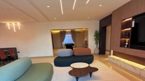 A modern living room with a sofa set, a coffee table, and a TV mounted on the wall.