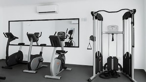 A modern gym with exercise equipment, a mirrored wall, and a bench.