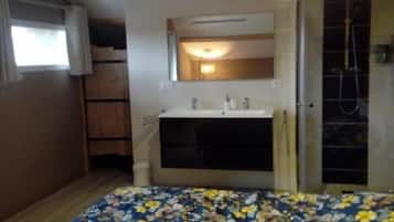 Un dormitorio con cama, un baño con ducha y una ventana.