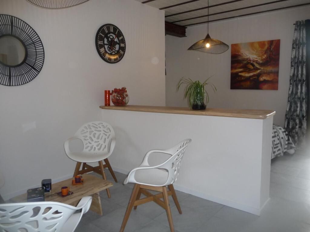Une pièce moderne avec une table en bois, deux chaises blanches, une petite plante et un tableau au mur.