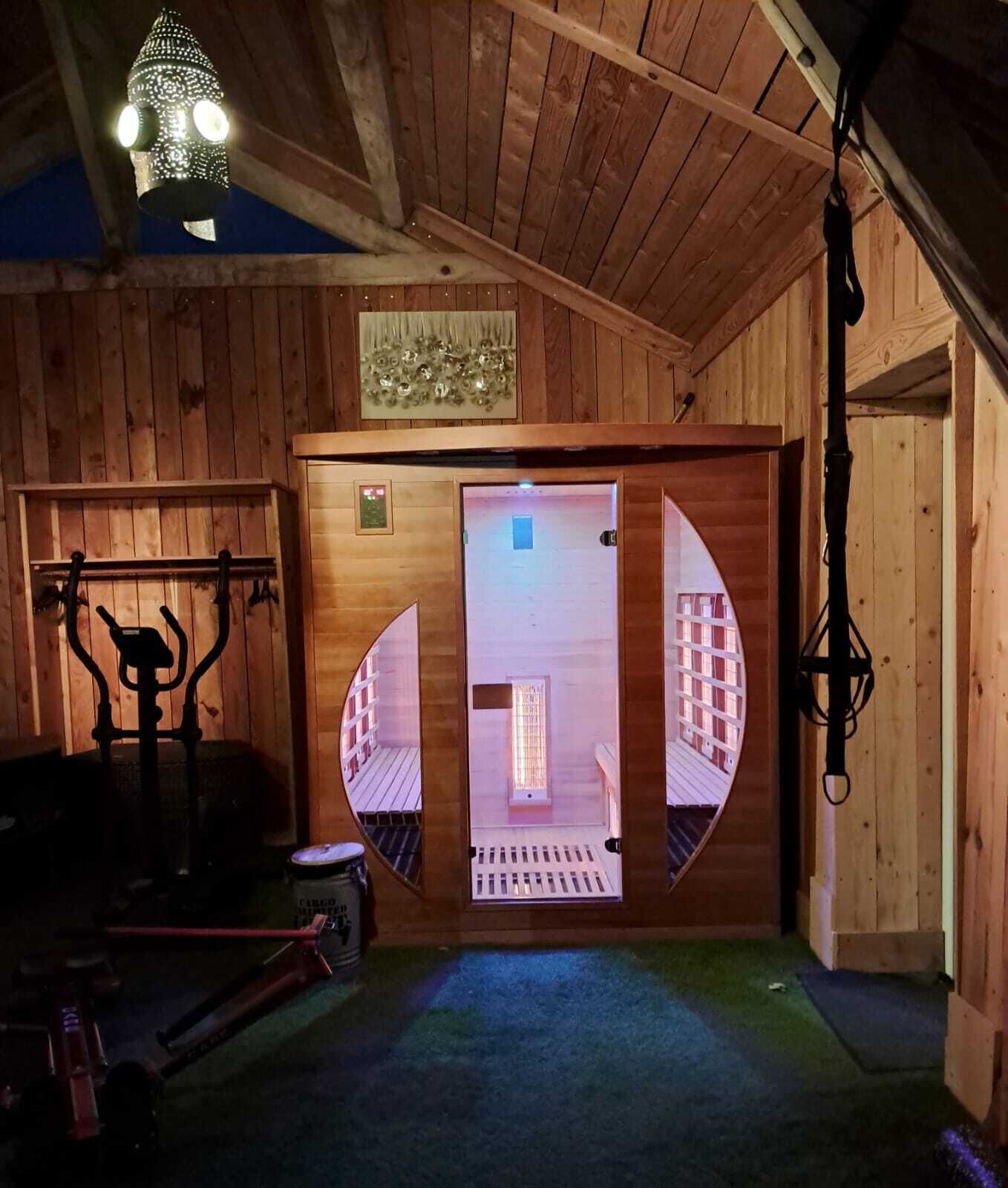 Interior de madera con un espejo que refleja una habitación, una lámpara colgante y una puerta con un ventanal.