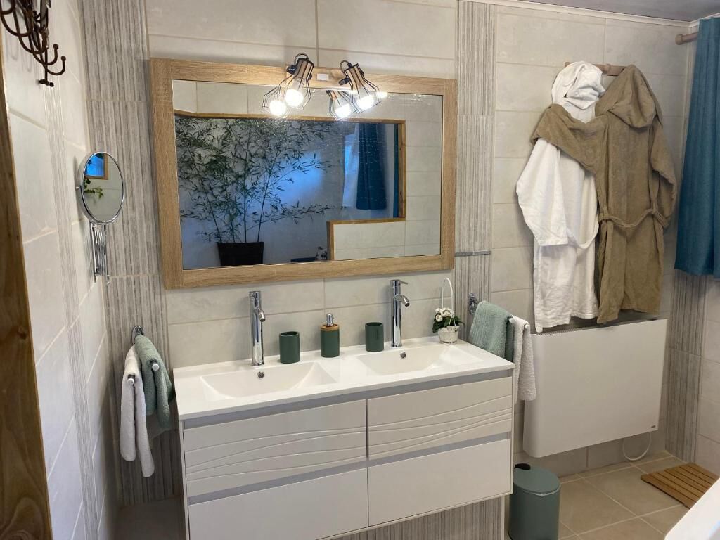 A modern bathroom with a large mirror, two sinks, and a towel rack.