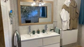 A modern bathroom with a large mirror, two sinks, and a towel rack.