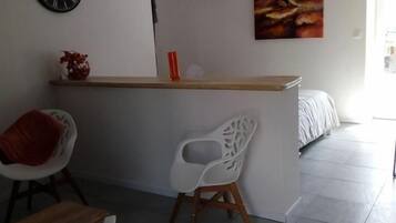 Cozinha moderna com ilha central, cadeiras brancas, um relógio e um quadro na parede.