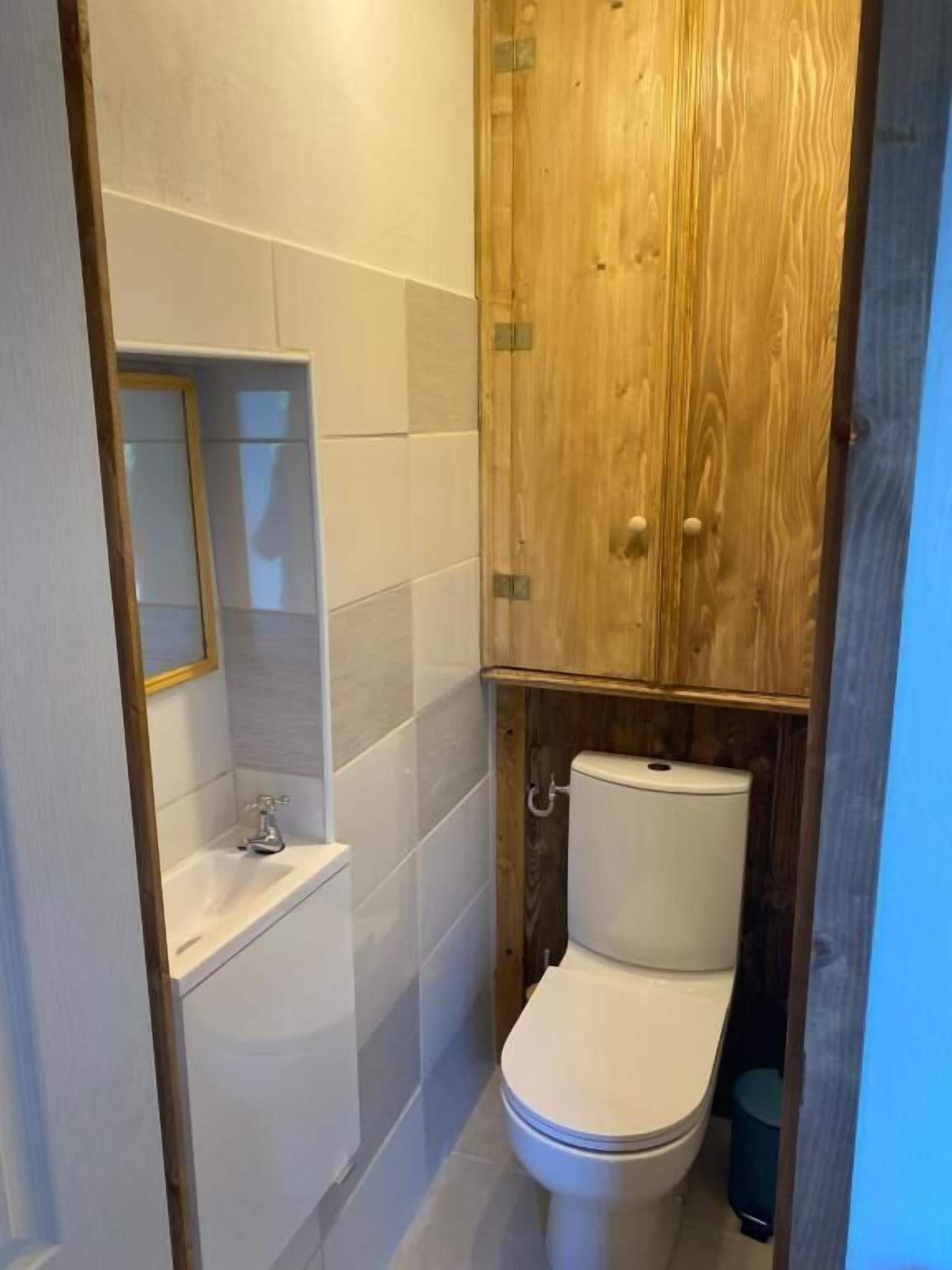 Un baño pequeño con inodoro, lavamanos y un mueble de madera.