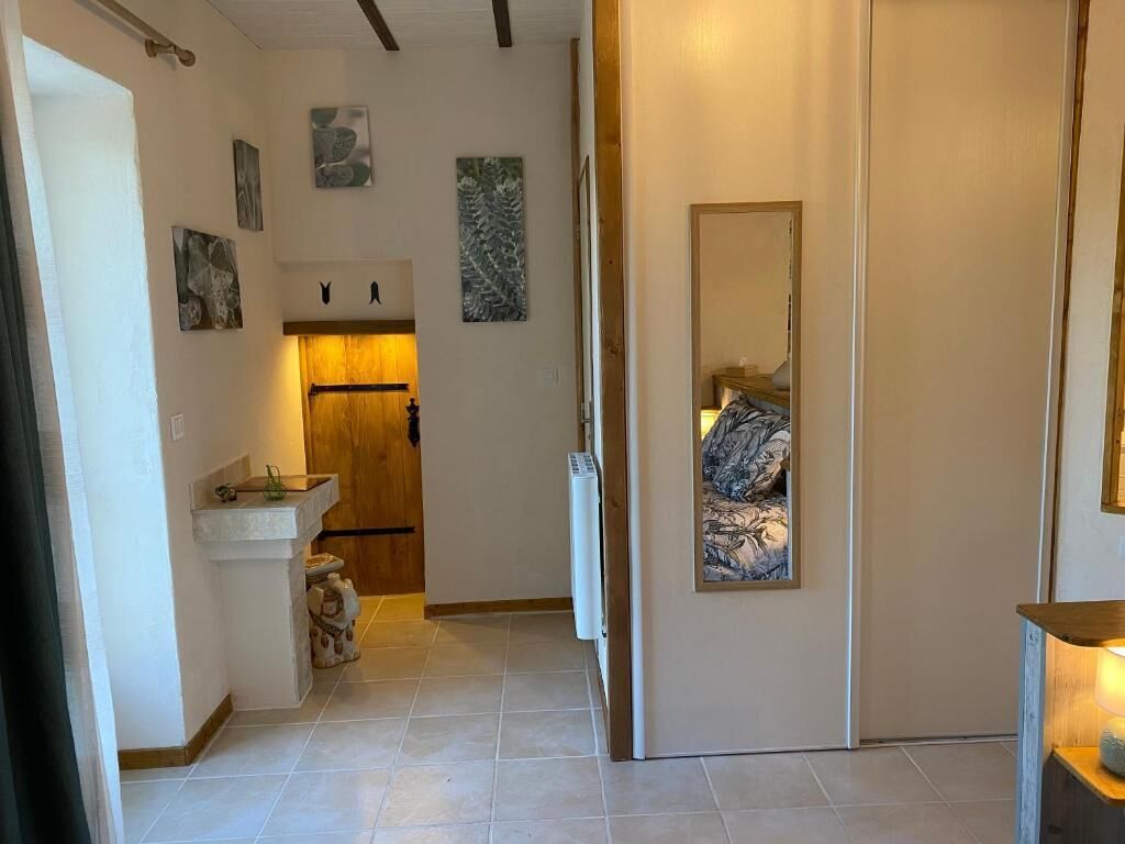 Un pasillo con una puerta de madera, un espejo y una cama con edredón estampado.