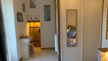 Un pasillo con una puerta de madera, un espejo y una cama con edredón estampado.