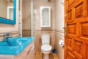 Ein Badezimmer mit blauem Waschbecken, weißer Toilette und Holztür.