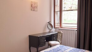 Una camera da letto con un letto, una cassettiera, uno specchio e una finestra con tende.