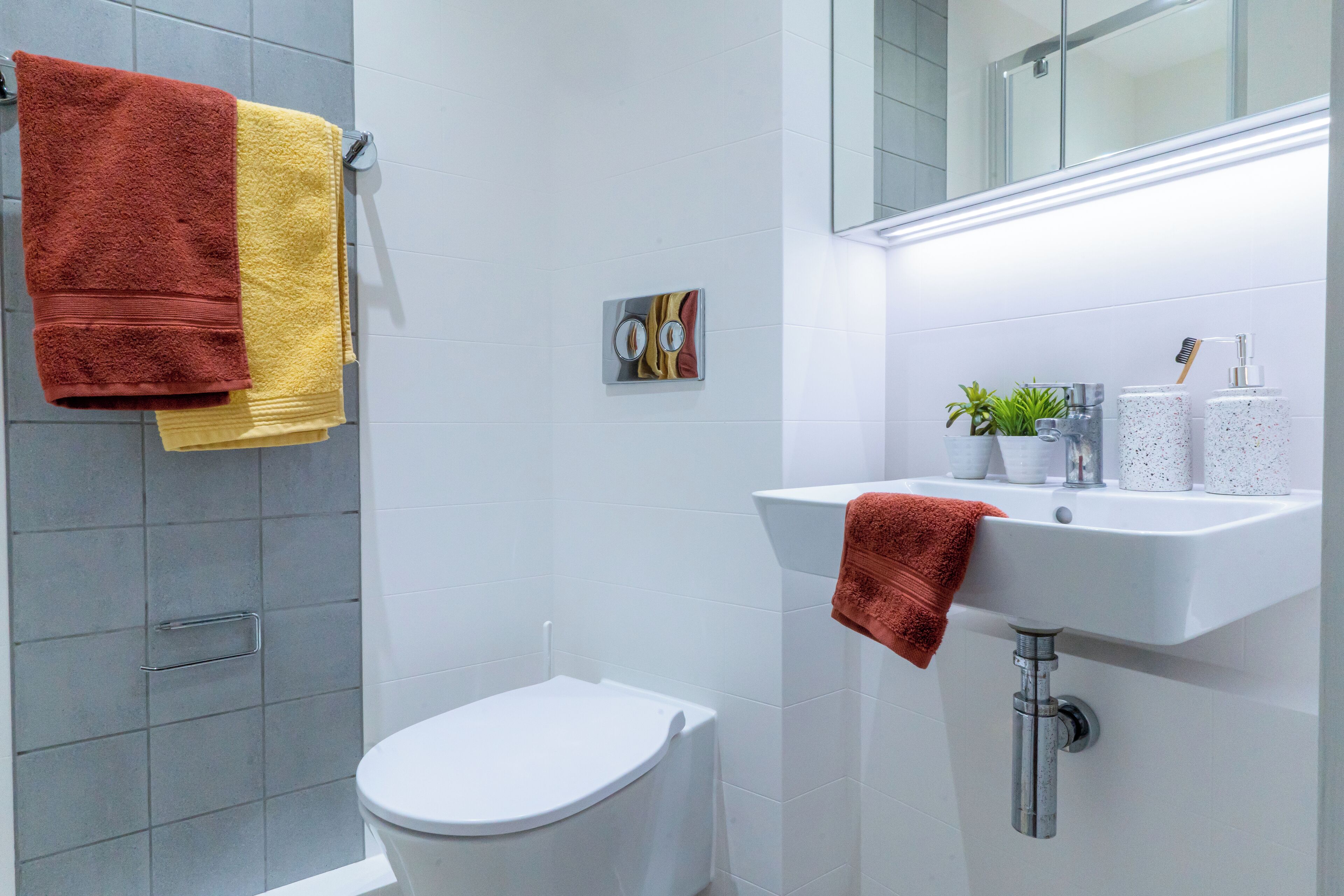 Ein modernes Badezimmer mit Toilette, Waschbecken mit Handtuch und Duschbereich.