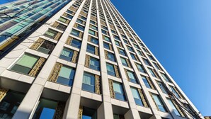 Un edificio alto y moderno con una rejilla de ventanas y detalles decorativos.