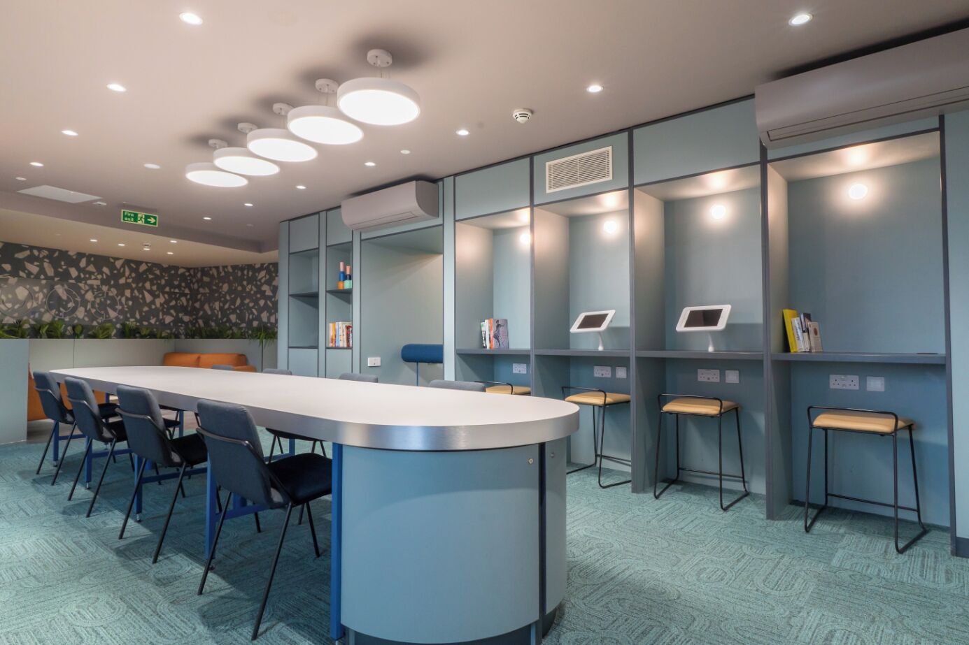 A modern conference room with a long table, chairs, and a counter with stools.