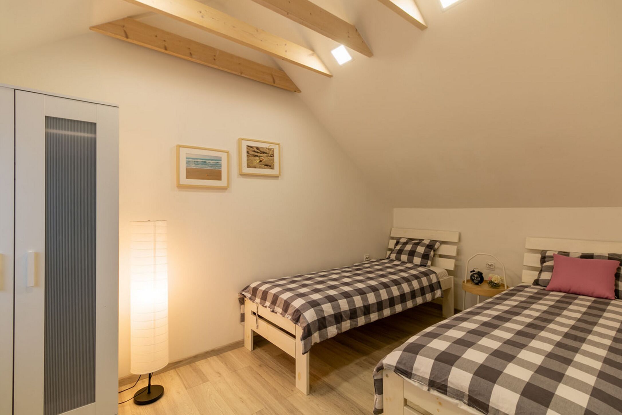 Ein Schlafzimmer mit zwei Betten, einem Kleiderschrank und einer Stehlampe.