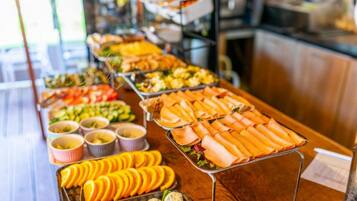 Buffet com diversos alimentos, incluindo frutas, vegetais e pratos com carne.