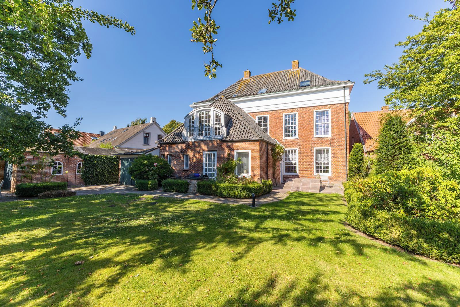 Une grande maison en briques, dotée d’une pelouse bien entretenue et d’un petit jardin.