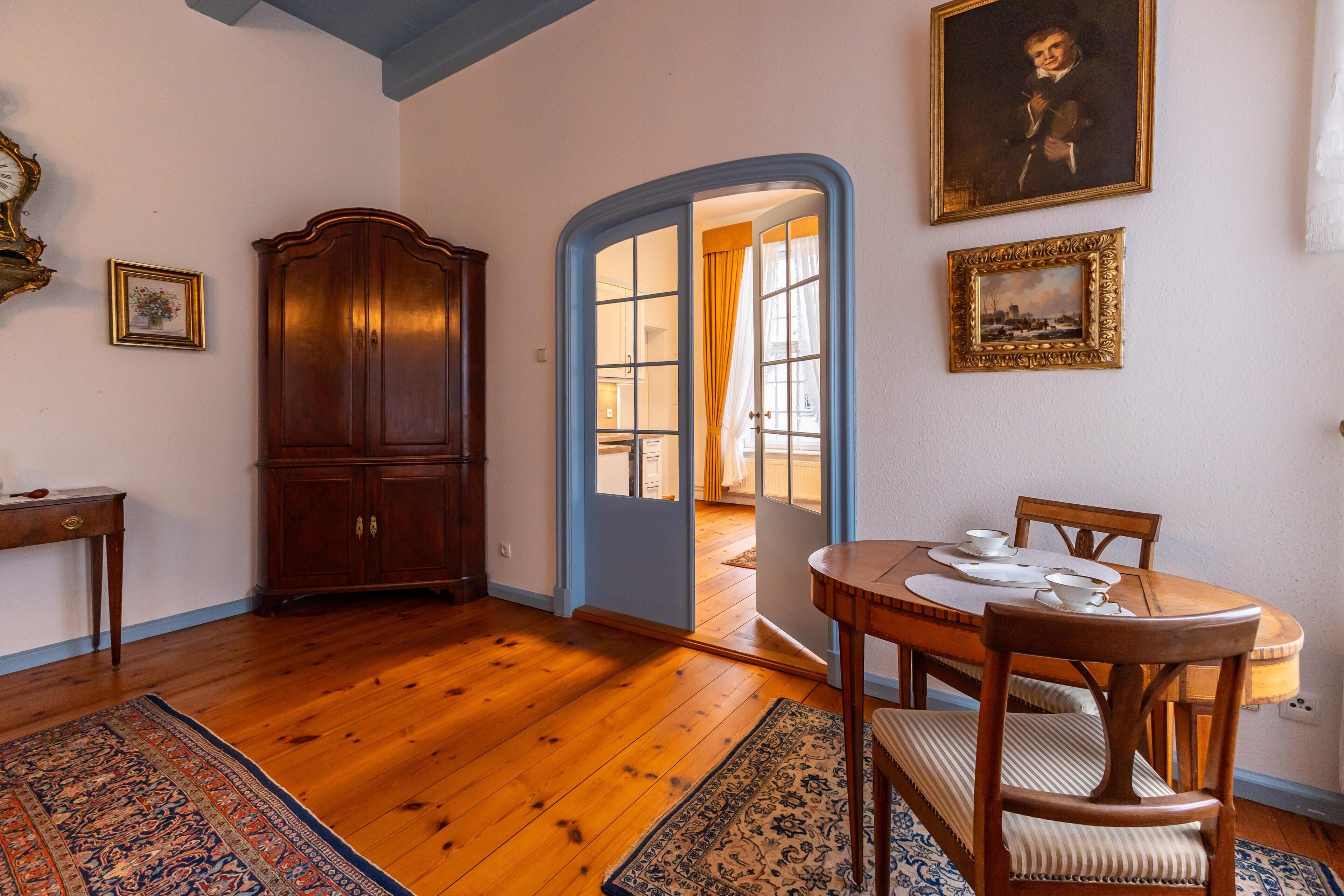 Uma sala de jantar com uma mesa de madeira, cadeiras e um tapete.
