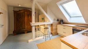 A kitchen with a wooden cabinet, a window, a stove, and a sink. - Vacation apartment "Attena" - Living above the rooftops of Greetsiel (Krummhörn)