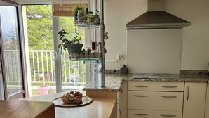 Una cucina con un tavolo di legno, un lavello, un fornello e una finestra vista alberi.
