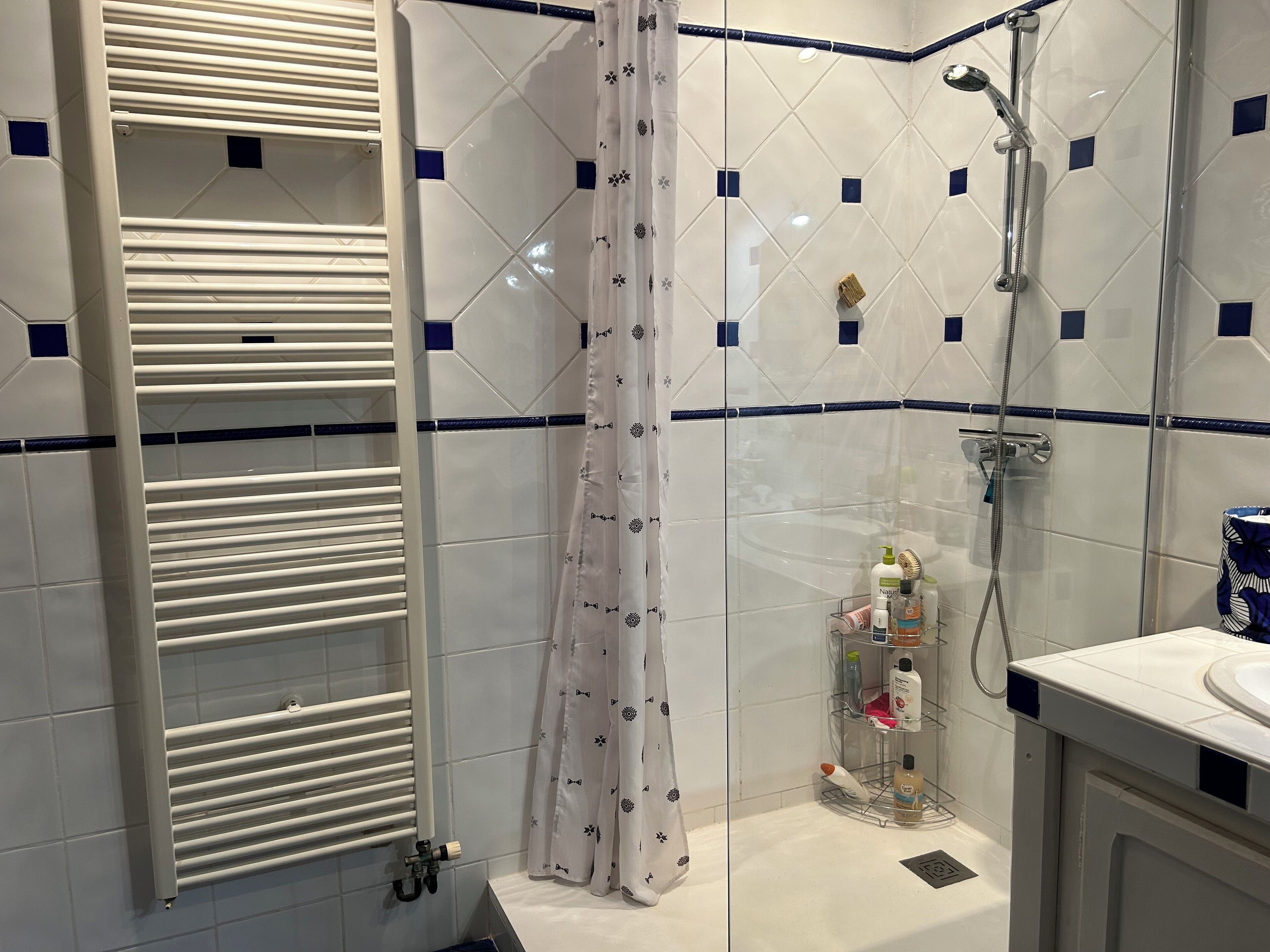 A bathroom with a shower, a towel rack, and a shelf with toiletries.