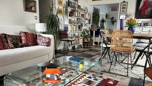 Un soggiorno con divano, tavolino, poltrone, una libreria e un tappeto decorato.