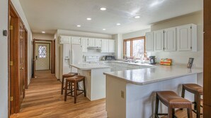 Une cuisine spacieuse avec des meubles blancs, un grand îlot central doté de tabourets et un plancher en bois.