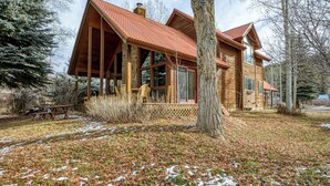 Une cabane en bois avec un toit rouge, de grandes fenêtres et une véranda couverte.