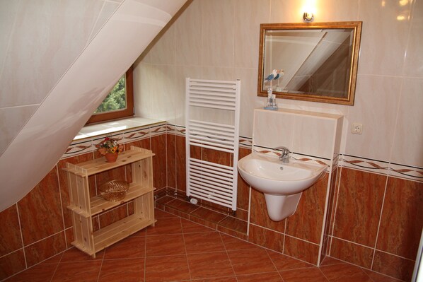 Une salle de bain avec un lavabo blanc, un miroir et un porte-serviettes.
