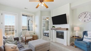 A living room with a fireplace, a television, and a clock on the wall. - Stone Cliff Oasis Scenic Views (Branson)
