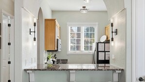 A compact kitchen with a granite countertop, wooden cabinets, and a window with blinds. - Stone Cliff Oasis Scenic Views (Branson)
