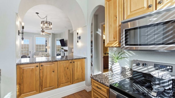 A kitchen with wooden cabinets, a stainless steel microwave, and a black stove. - Stone Cliff Oasis Scenic Views (Branson)