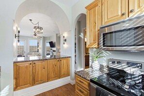 A kitchen with wooden cabinets, a stainless steel microwave, and a black stove. - Stone Cliff Oasis Scenic Views (Branson)