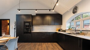 Uma cozinha moderna com armários escuros, forno embutido e uma janela ampla que traz luz natural.