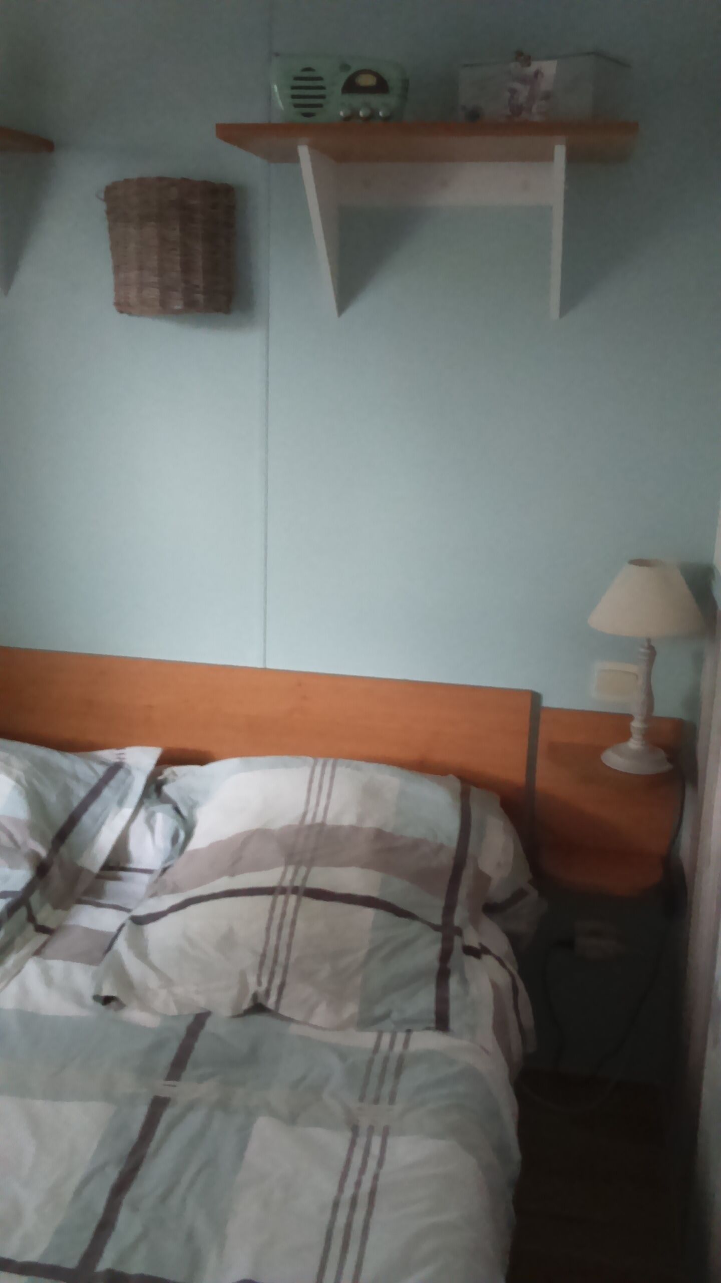 Una camera da letto con un letto, un comodino, una lampada e uno scaffale con una radio.