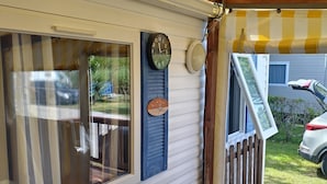 A covered porch with a wooden deck, a clock, and a lantern. - Seasonal rental fully equipped mobile home for 4/6 people (Saint-Hilaire-de-Riez)