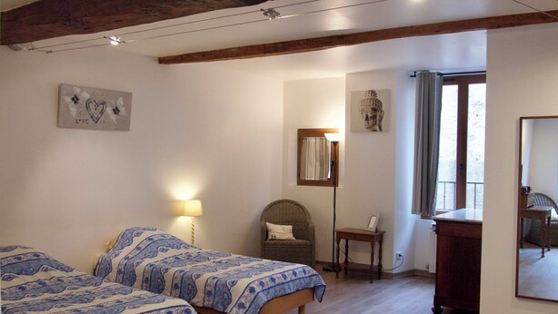 Ein Zimmer mit zwei Betten, einem Sessel, einem Schreibtisch, einem Spiegel und einem Buddha-Gemälde.