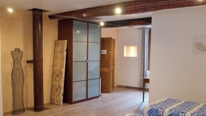 Ein Zimmer mit einem Bett, einem Kleiderschrank und einer Tür zu einem anderen Raum.