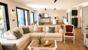 A modern living room with a sectional sofa, a dining table, and a kitchen in the background.