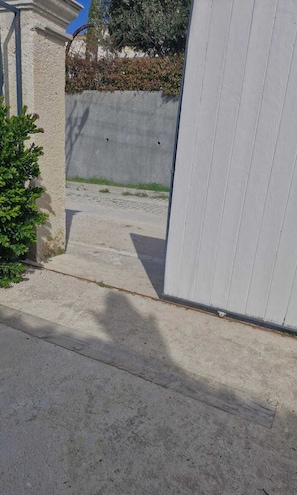 Un sendero de hormigón que conduce a un edificio con fachada blanca.