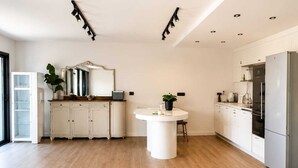 A modern kitchen with white cabinetry, a central island, and a stainless steel refrigerator.